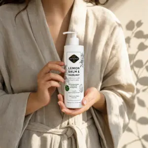 Frau im Leinenmantel hält die Conditioner-Flasche in beiden Händen, Schatten von Blattwerk auf dem Stoff